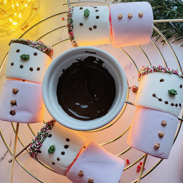 Four snow women marshmallows dipped in melted chocolate and sprinkles