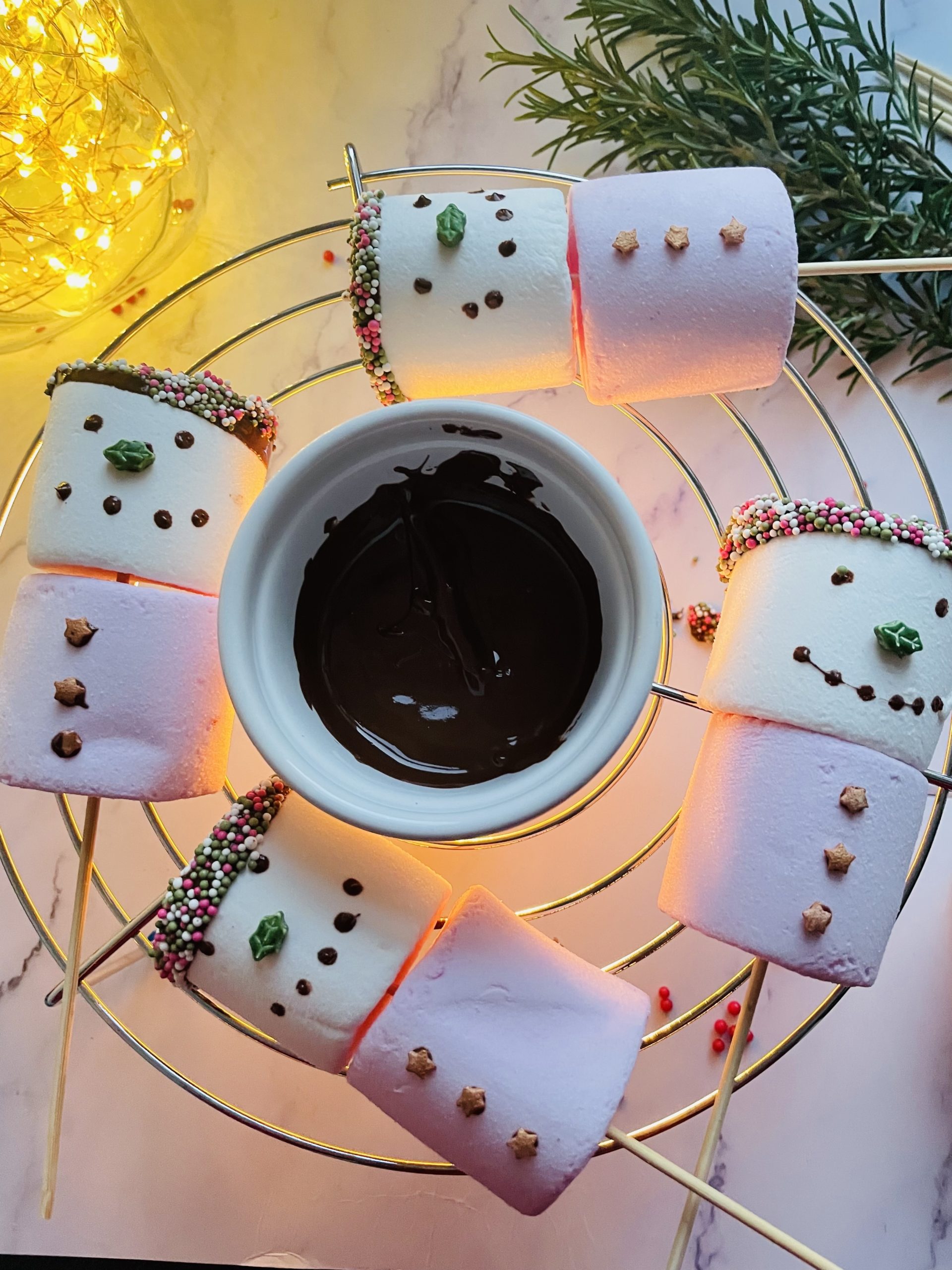 Four snow women marshmallows dipped in melted chocolate and sprinkles